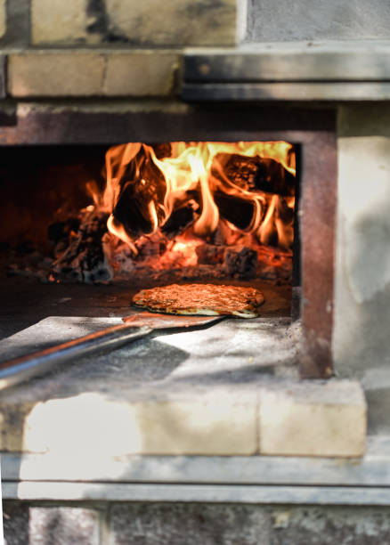 istock Cooked pizza being pulled from a wood fired pizza oven outdoors. 1344259836