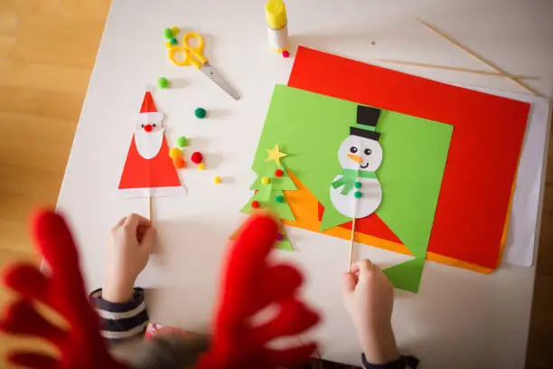 Photo of paper craft for kids. girls play with homemade toys Santa Claus and snowman. create fun art for children. new year concept