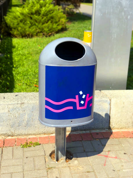 Blue metal trash can with ashtray near the lawn. Urban environmental care concept. Modern stylish waste bin on the tiled brick sidewalk as an element of city infrastructure. Dnipro, Ukraine, 2021. bote de basura de metal azul con cenicero cerca del césped. concepto de cuidado del medio ambiente urbano. moderno y elegante contenedor de basura en la acera de ladrillo de azulejos como un o de la infraestructura de la ciudad. dnipro, ucrania, 20