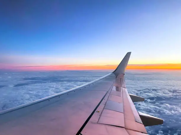 Photo of Colourful sunrise over wing of modern jet airliner towards the horizon