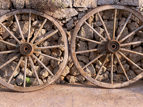 Large ancient wooden spoked cartwheels lean against a handmade drystone wall, Majorca, Balearic islands, Spain