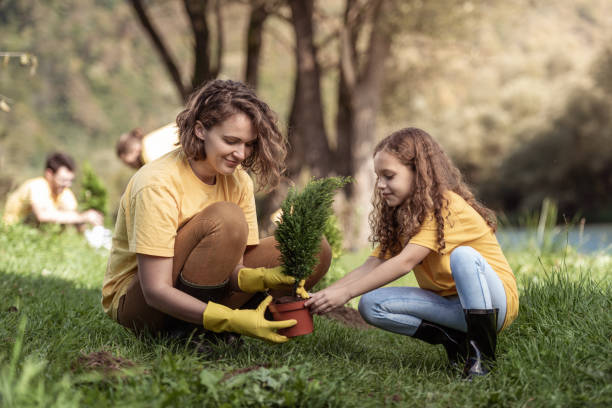 istock Mother and daughter planting a tree by river 1344270633