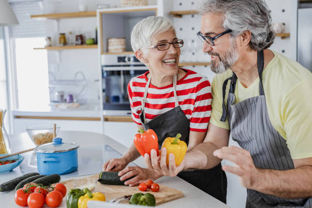 pareja de ancianos cocinando juntos en casa - cooking senior adult healthy lifestyle couple fotografías e imágenes de stock