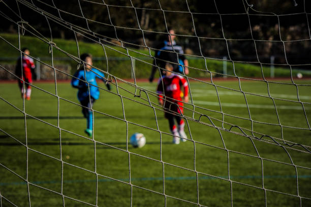 Young boys playing football - pictured through a goal net