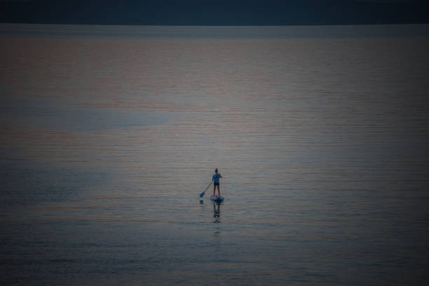 Person does stand up paddling on a lake in the evening sun