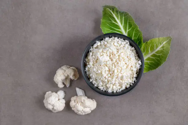 Cauliflower rice on gray stone background, selective focus, top view.