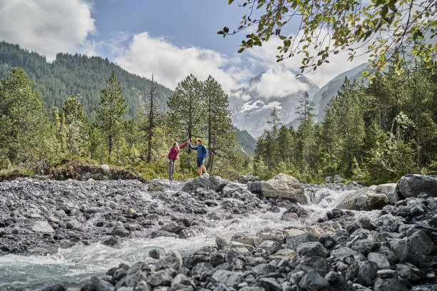 istock Friends hike down rocky trail towards flowing river 1344281515