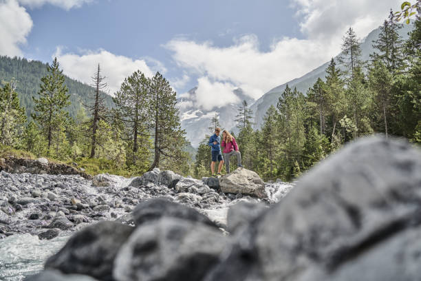 istock Friends hike down rocky trail towards flowing river 1344282210