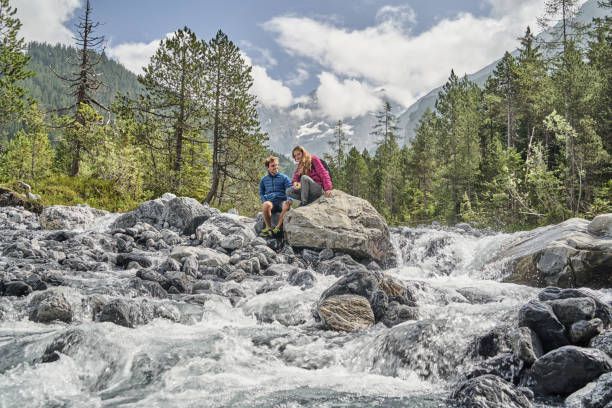istock Friends relax on rock formation near flowing river 1344282238