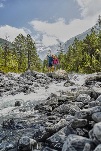 istock Friends hike down rocky trail towards flowing river 1344282378