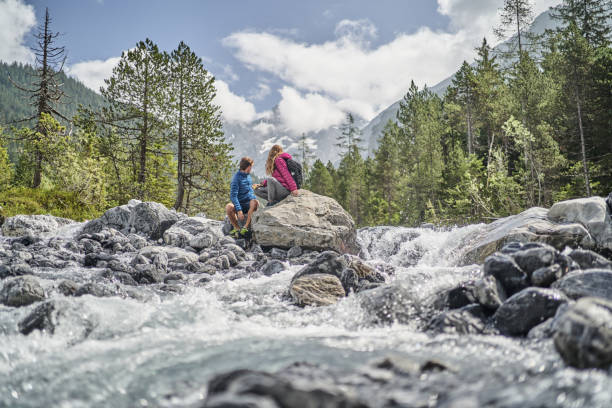 istock Friends relax on rock formation near flowing river 1344282414
