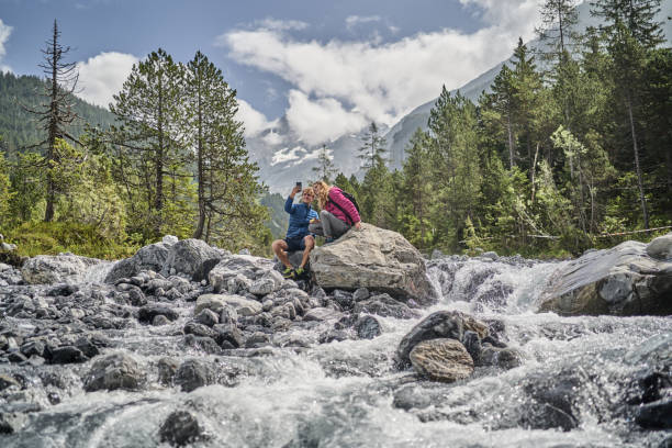 istock Friends relax on rock formation near flowing river 1344282566
