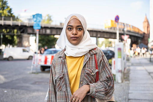 portrait of young woman with hijab in front of  Oberbaumbrücke in Berlin Kreuzberg at sunny late summer day