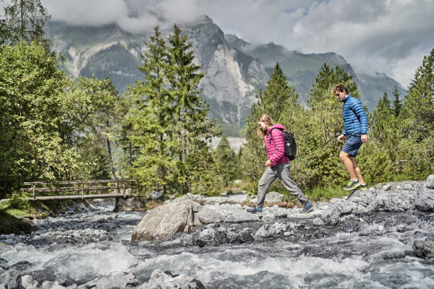 istock Friends hike down rocky trail towards flowing river 1344282750