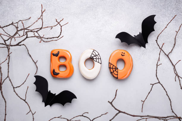 istock Text BOO from gingerbread cookies, Halloween decorations, paper bat on stone background. Halloween concept 1344282758