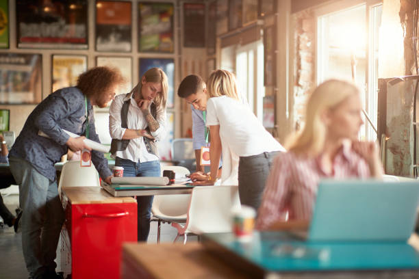 istock selective focus on group of young adult people gathered around the table, analyzing new design with teamleader 1344284162