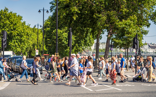 A large number of pedestrians crossing the street in Westminster, on a sunny day in central London.