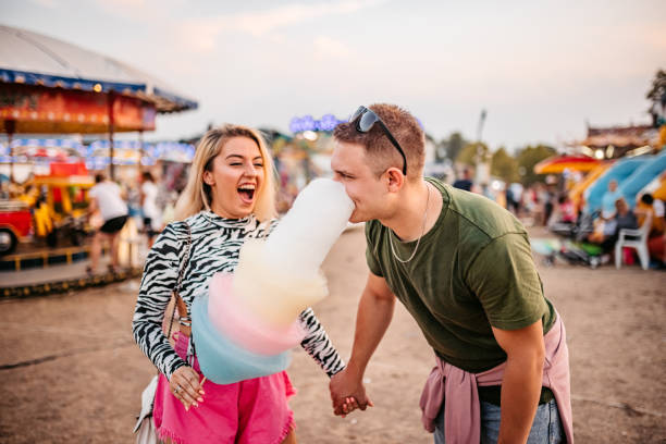 istock Couple sharing cotton candy at amusement park 1344290527