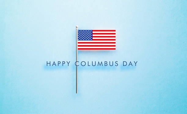 istock Happy Columbus Day Message Next to Tiny American Flag on Blue Background 1344294043