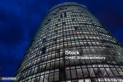 istock Rising skyward from street below high-rise commercial office building at night with light in all windows. 1344295810