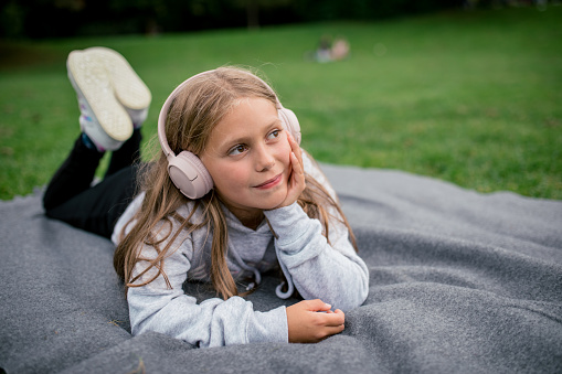 Girl with headphones in the park listens to music