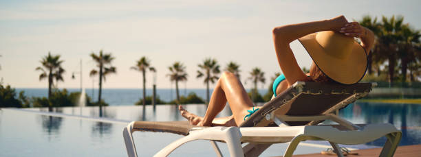 istock Woman near pool tanning on deck chair 1344298367