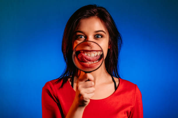 istock Woman in holding loupe showing teeth through 1344299236
