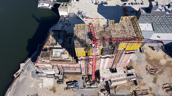 Aerial, drone views of a construction site on the edge of the East River in Brooklyn, New York on a sunny day. This part of Brooklyn is being built up because of the beautiful views of Manhattan's East side across the river.