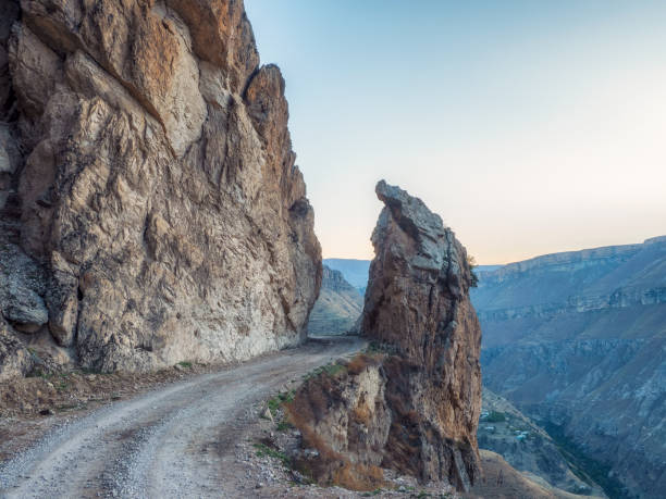 Dangerous narrow cliffside mountain road through sharp rocks.. Dangerous off road driving along mountain edge and steep cliff. Dagestan.