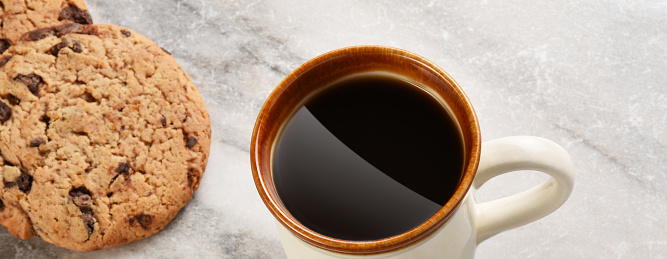 Almond cookies with hot black coffee on wooden table and morning light