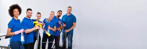 Portrait Of Happy Male And Female Janitors With Cleaning Equipment