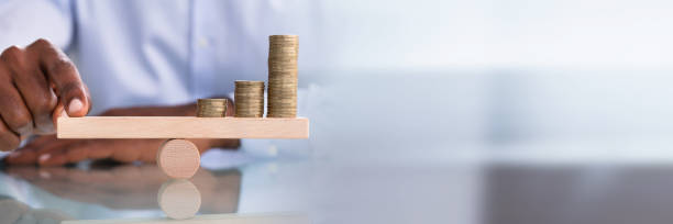istock Businessman Balancing The Coin Stack On Wooden Seesaw 1344305316