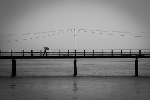 a man crosses a bridge when it rains