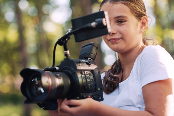 istock Cute girl shooting a video with a professional video camera 1344310995