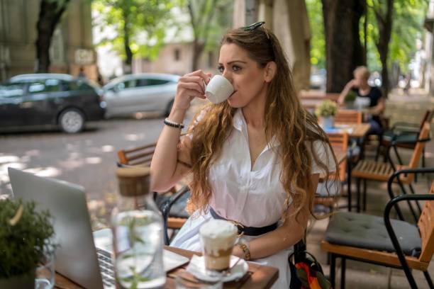 istock Businesswoman using laptop while enjoying work at cafe table with cup of coffee 1344311079