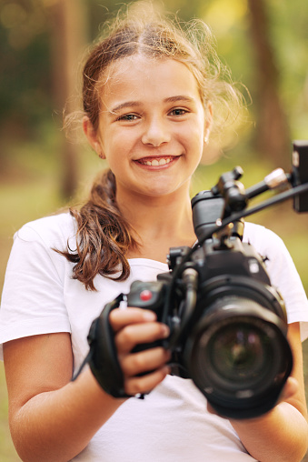 Cute girl walking in the forest and shooting a video using a professional video camera