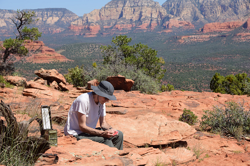 A man has just found and opened a hidden geocache in the wilderness of Sedona, Arizona.