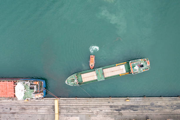 luftaufnahme des frachtschiffes, das sich mit einem schlepper dem hafen nähert. - piloting commercial dock harbor industrial ship stock-fotos und bilder