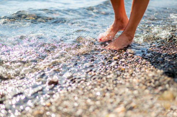 End of summer - close up shot of legs of a woman, walking at the beach during sunset