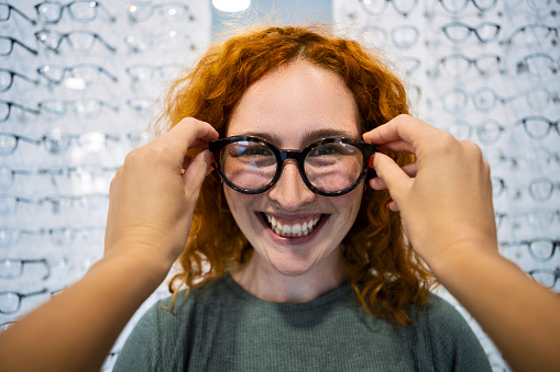Young woman trying on a new pair of glasses at an optic store