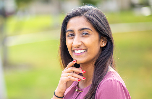 Happy indian girl looking at camera by holding Diya lamp during Diwali festival celebration on decorated background - concept of traditional culture, greetings and spirituality or harmony.