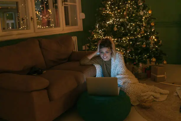 Photo of a young woman watching movies and enjoying her Christmas Eve at home alone.