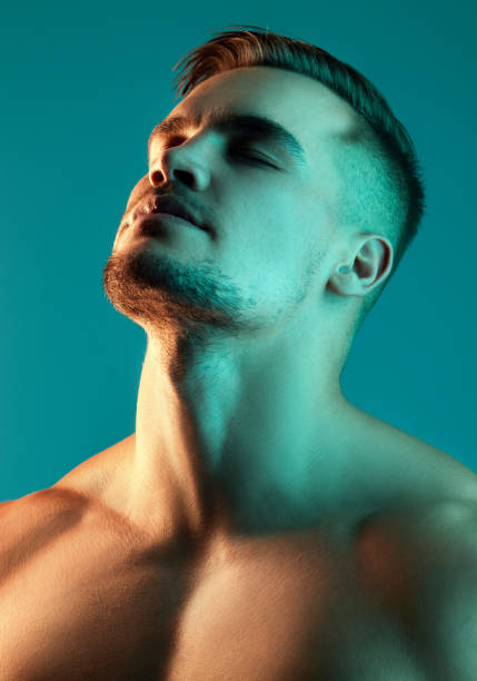 studio shot of a handsome young man posing against a blue background - sensuality men shirtless studio shot imagens e fotografias de stock