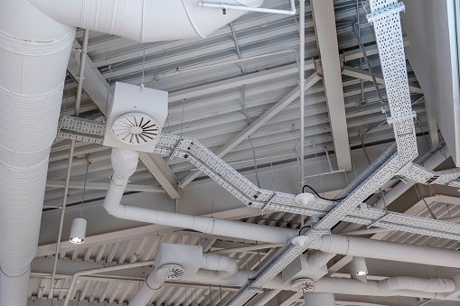Ventilation system under ceiling of modern warehouse or shopping center. Metal piping for air conditioning