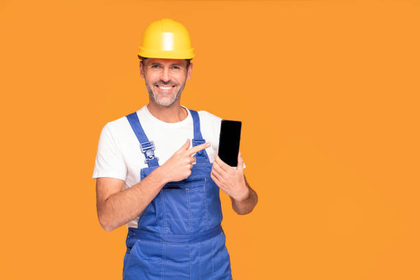 istock Smiling Construction Worker Showing Cellphone Empty Screen to the camera. 1344327319