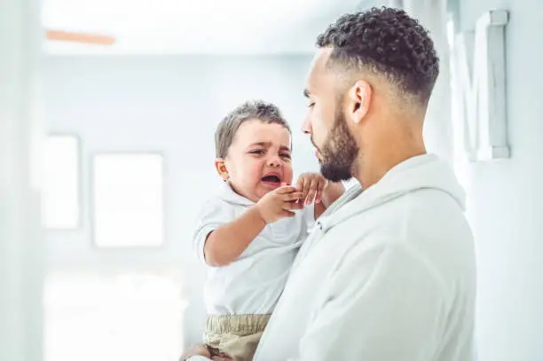 Cute kid having a fit being held by his father