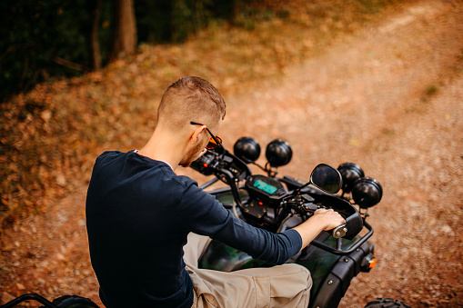 Young men driving quad on the hill