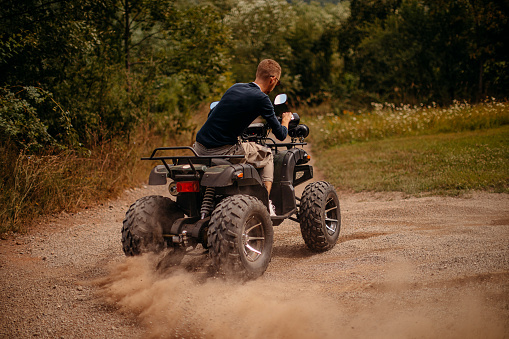 Young men driving quad on the hill