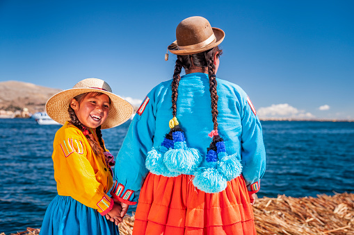 Madre y su hija mirando a la vista en la isla flotante de los Uros, Lago Tititcaca, Perú photo