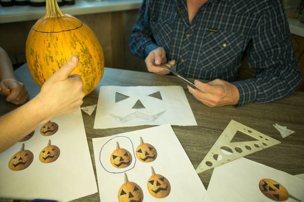 istock Making Jack O'Lantern at home. The process of creating a Jack O'Lantern theme template. A man and a woman are preparing a pumpkin for carving. 1344330567
